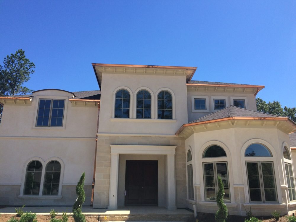 Two-story stucco home with copper gutters along each roofline