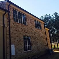 Dark downspouts running down a two-story brick wall