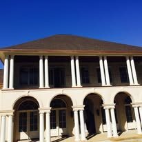 Two-story home with columns and arched openings and gutters at both roof levels
